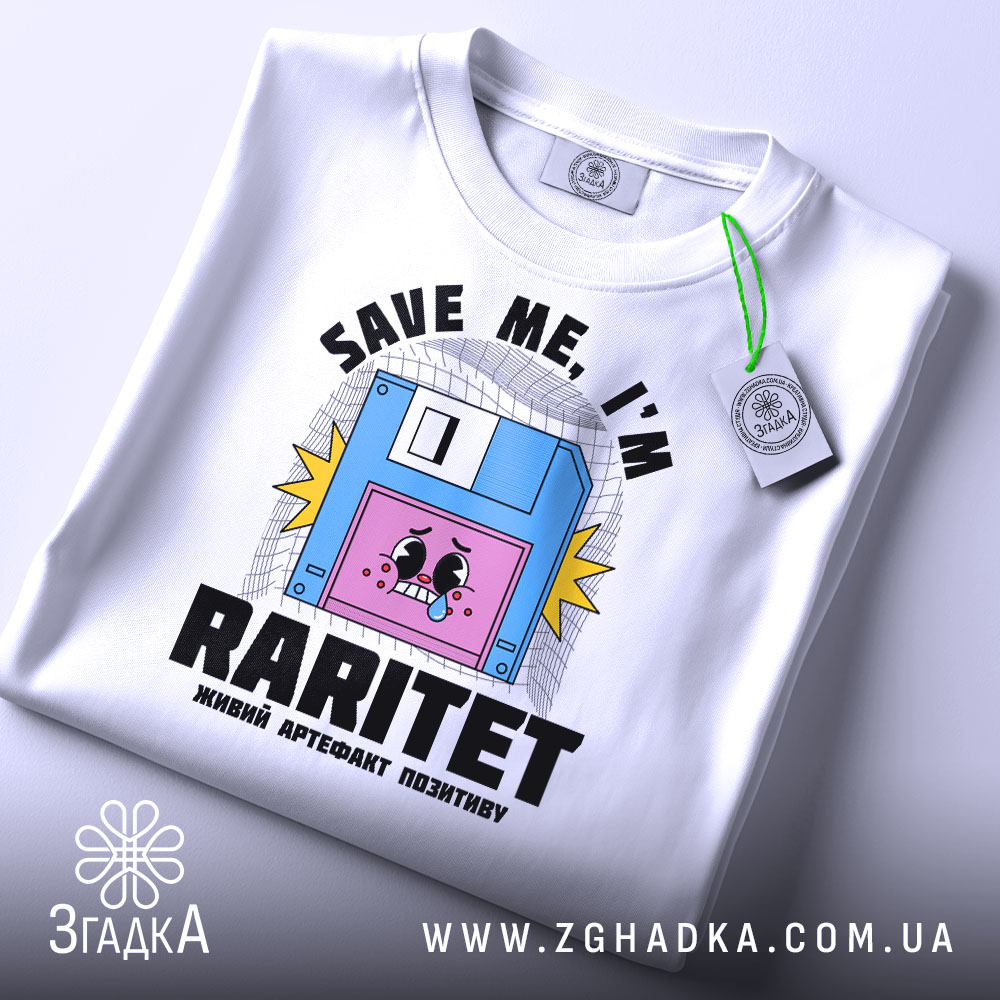 Футболка раритет живий артефакт, біла, зображена в складеному вигляді, фон світло-сірий, принт з веселим обличчям на дискеті та написом 'SAVE ME, I'M RARITET', прикріплена етикетка з зеленим шнурком.