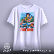 Футболка Рембо перша кров білого кольору, зображена на вішалці з фронтального ракурсу, фон світло-сірий, принт яскравий, з персонажами та написом 'FIRST BLOOD'.