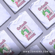 Футболка режим Грінча, біла, зображена з фронтального ракурсу, фон градієнтний сірий, принт з зеленим рукою Грінча, що натискає на вимикач, текст 'ON OFF MODE' в рожевих і зелених кольорах.