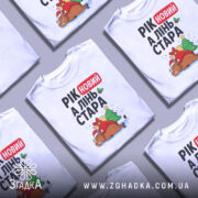 Футболка рік новий, біла, зображена на манекені, фон градієнтний сірий, принт з оленем у червоному капелюсі, ялинкою та подарунками, текст "РІК новий А ЛІНЬ СТАРА".