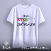 Футболка різдвяний прогрес, біла, зображена з фронтального ракурсу на вішалці, фон світлий, принт містить напис 'LOADING...' та малюнок ялинки на смужці з червоними і білими смугами.