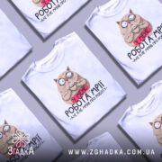 Футболка робота мрії, білого кольору, зображена на манекені з правого боку, фон світло-сірий, принт з котом, який тримає чашку, з текстом 'У МЕНЕ РОБОТА МРІЇ - АЛЕ Я НЕ МРІЯВ ПРО РОБОТУ'.