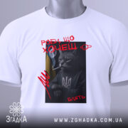 Футболка роби що хочеш, біла, складена на поверхні, фон світло-сірий, принт з котом у свитері з тризубом, котяча фігура з сигаретою, текст червоним кольором, на комірці видна етикетка.