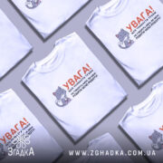 Футболка робити мою роботу. Біла футболка з коротким рукавом, зображена з фронтального ракурсу на манекені. На фоні світло-сірий колір. Принт містить малюнок котика з ножицями та текстом, що попереджає про обережність.