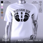 Футболка родинний гумор, біла, зображена на манекені, фон нейтральний, принт з чорними слідами ніг і текстом 'JUST HERE FOR SEX'.