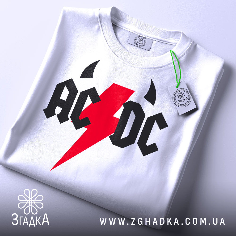 Футболка рок енергія, біла, складена на поверхні, фон світло-сірий, принт з червоним блискавкою та чорними літерами 'AC/DC', з етикеткою на зеленому шнурку.