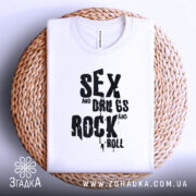 Футболка рок стиль, біла, зображена зверху на плетеній основі, фон світло-сірий, принт чорний з написом 'SEX and DRUGS and ROCK n' ROLL'.