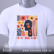 Футболка розквіт особистості. Біла футболка, складена на столі, з етикеткою, що звисає. На фоні світло-сірий колір. Принт з абстрактним обличчям, оточеним кольоровими квітами, виконаний в яскравих кольорах.