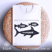 Футболка розмір має значення, біла, складена на плетеній кошику, принт з рибами та написами "РОЗМІР", "МАС" і "ЗНАЧЕННЯ" у чорному кольорі, фон нейтральний.