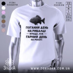 Футболка рибалка жарт. Біла футболка з коротким рукавом, зображена з близького ракурсу. На фоні видно світло-сірий градієнт. Принт з чорним текстом і малюнком риби розташований по центру.