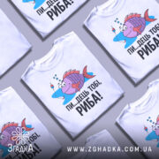 Футболка рибальський настрій. Біла футболка з принтом, на якому зображена риба з великими очима, що плаває у воді, з поплавком поруч. Принт яскравий, з веселими кольорами, текст чорного кольору: 'ПИ...ДЕЦЬ ТОБІ, РИБА!'. Фон нейтральний, манекен з футболкою стоїть на світлому фоні.