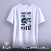 Футболка риболовля це життя. Біла футболка, підвішена на вішалці, з принтом спереду. Ракурс спереду, фон світлий, деталі принта чітко видимі.