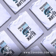 Футболка риболовля це життя. Біла футболка з принтом, на якому зображена риба та текст. Ракурс спереду, фон нейтральний, деталі принта включають рибу та напис у стилі графіті.