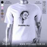 Футболка Сальвадор Далі білого кольору, зображена з фронтального ракурсу на манекені, фон градієнтний сірий, принт з портретом Сальвадора Далі в чорному кольорі, підпис 'SALVADOR DALI' внизу.