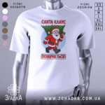 Футболка Санта Клаус повернеться, біла, зображена з фронтального ракурсу, фон нейтральний, принт з веселим Санта Клаусом, який несе ялинку, текст червоним кольором: 'Санта КЛАУС ПОВЕРНЕТЬСЯ!'