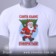 Футболка Санта Клаус повернеться, біла, зображена з верхнього ракурсу, фон світлий, принт з Санта Клаусом, який біжить з ялинкою, текст червоним кольором: 'Санта КЛАУС ПОВЕРНЕТЬСЯ!', на футболці є етикетка з зеленим шнурком.