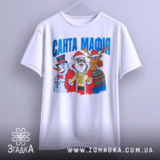 Футболка Санта Мафія білого кольору, підвішена на вішалці, ракурс спереду, фон світло-сірий, принт з Сантою, сніговиком і оленем, текст "САНТА МАФІЯ" вгорі.