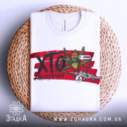 Футболка сарана, біла, зображена на плетеній кошику, фон світло-сірий, принт з зеленим саранчою та сірим ящіркою на червоному фоні з написом "ХТО?".