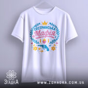 Футболка сестринська мафія білого кольору, підвішена на вішалці, фон світло-сірий, принт яскравий з написом 'Сестринська Мафія', пістолетом, кулі, квіти та сердечка.