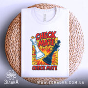 Футболка шах і мат, біла, зображена зверху, на фоні світло-сірого кольору, принт з шаховими фігурами та текстом 'CHECK MATE', розташована на плетеній кошику.