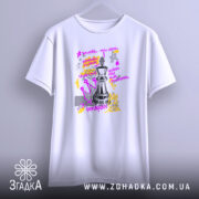 Футболка шахова стратегія, біла, підвішена на вішалці, фон світлий, принт з шаховою фігурою та кольоровими елементами, текст на принті написаний фіолетовим та жовтим кольором.