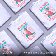 Футболка шалена бабуля, білого кольору, зображена з правого ракурсу на манекені, фон світло-сірий, принт з бабусею, що тримає келих, в яскравих кольорах.