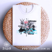 Футболка щаслива вільна, білого кольору, складена на плетеній основі, фон світлий. Принт містить зображення птаха з короною, серцем та абстрактними елементами в чорному і блакитному кольорах.