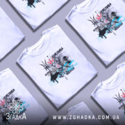 Футболка щаслива вільна, білого кольору, зображена на манекені з ближнього ракурсу, фон нейтральний. Принт містить малюнок птаха з короною, серцем та елементами чорного і блакитного кольору.