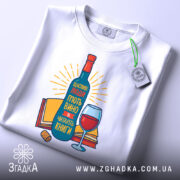 Футболка щасливі люди, білого кольору, зображена зверху, на ній видно етикетку, фон світло-сірий, принт з пляшкою вина, келихом та книгами, яскраві кольори, текст на українській мові.