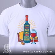 Футболка щасливі люди, білого кольору, зображена зверху, на ній видно етикетку, фон світло-сірий, принт з пляшкою вина, келихом та книгами, яскраві кольори, текст на українській мові.