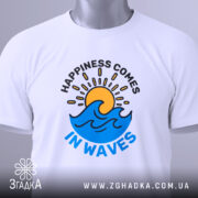 Футболка щастя у хвилях, біла, зображена зверху, складена, фон світлий, на футболці принт з сонцем і хвилями, з етикеткою на зеленому шнурку.