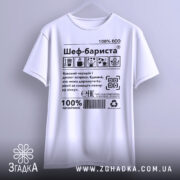 Футболка шеф бариста білого кольору, підвішена на вішалці, фон нейтральний, принт містить текст і графічні символи, напис '100% ECO'.