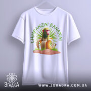Футболка Shimpanzini Bananini білого кольору, зображена на вішалці, фон світло-сірий, принт з мавпою на банані оточений зеленими рослинами, вид спереду.