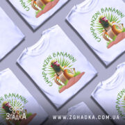 Футболка Shimpanzini Bananini білого кольору, зображена з фронтального ракурсу на манекені, фон світло-сірий, принт з мавпою на банані оточений зеленими рослинами.