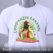 Футболка Shimpanzini Bananini білого кольору, зображена з верхнього ракурсу, на ній видно принт з мавпою на банані, фон світло-сірий, на футболці є етикетка.