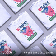 Футболка шубатого нового року, білого кольору, зображена на манекені, фон нейтральний, принт з рибою в рожевій шубі та написом, яскраві кольори, деталі принта включають сердечка та дорогоцінні камені.