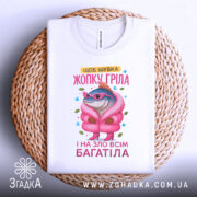 Футболка шубка жопку гріла, біла, зображена зверху на плетеній основі, фон світло-сірий, принт з рибою в рожевій шубі та окулярах, текст кольоровий.