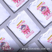 Футболка шубка жопку гріла, біла, зображена з фронтального ракурсу, фон світло-сірий, принт з веселою рибою в рожевій шубі та окулярах, текст жовтого кольору.