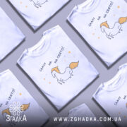 Футболка скачу на свято, біла, зображена на манекені, фон світло-сірий, принт з веселим єдинорогом з жовтими гривою та текстом 'скачу на свято!' у чорному кольорі.