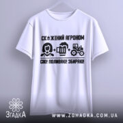 Футболка скажений агроном, біла, підвішена на вішалці, фон градієнтний сірий, принт чорного кольору з текстом і іконками, що зображують агронома, пиво та трактор.