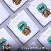 Футболка скелет з написом, біла, зображена на манекені, фон світло-сірий, принт з черепом, що тримає бінокль, кольори принта яскраві: оранжевий, чорний, блакитний.