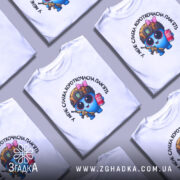 Футболка слабка пам`ять, біла, зображена на манекені з ближнього ракурсу, фон світлий, принт з веселим персонажем у військовій касці, з автоматом та банкою напою.