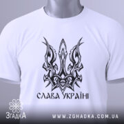 Футболка слава україні, біла, зображена зверху, на фоні світлого градієнту, принт у вигляді тризуба чорного кольору, з етикеткою зеленого кольору.
