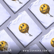 Футболка смайл у колючках, біла, зображена на манекені, фон світло-сірий, принт з жовтим смайлом у колючках, з краплями фарби.