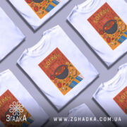 Футболка смак бограчу, біла, зображена на манекені, фон світло-сірий, принт з каструлею бограчу та овочами на помаранчевому фоні, деталі принта яскраві та кольорові.