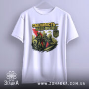 Футболка сміливість наш фронт, біла, підвішена на вішалці, фон світло-сірий, принт з трьома солдатами, червона смуга, логотип України в кутку.