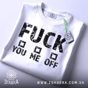 Футболка сміливий напис, біла, складена на столі, фон світло-сірий, принт чорний з грубими літерами, текст "FUCK YOU ME OFF" з квадратами, на комірці є етикетка.
