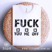 Футболка сміливий напис, біла, складена на плетеній кошику, фон світлий, принт чорний з грубими літерами, текст "FUCK YOU ME OFF" з квадратами.