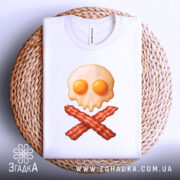 Футболка сніданок стиль, складена біла футболка на плетеній кошику, принт у вигляді черепа з яєчнею та хрестом з бекону, фон світлий, деталі принта чіткі.