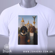 Футболка собаки мистецтво Києва, біла, зображена на столі, ракурс зверху, фон світлий, принт з двома собаками в одязі на фоні архітектури з золотими куполами, з етикеткою.